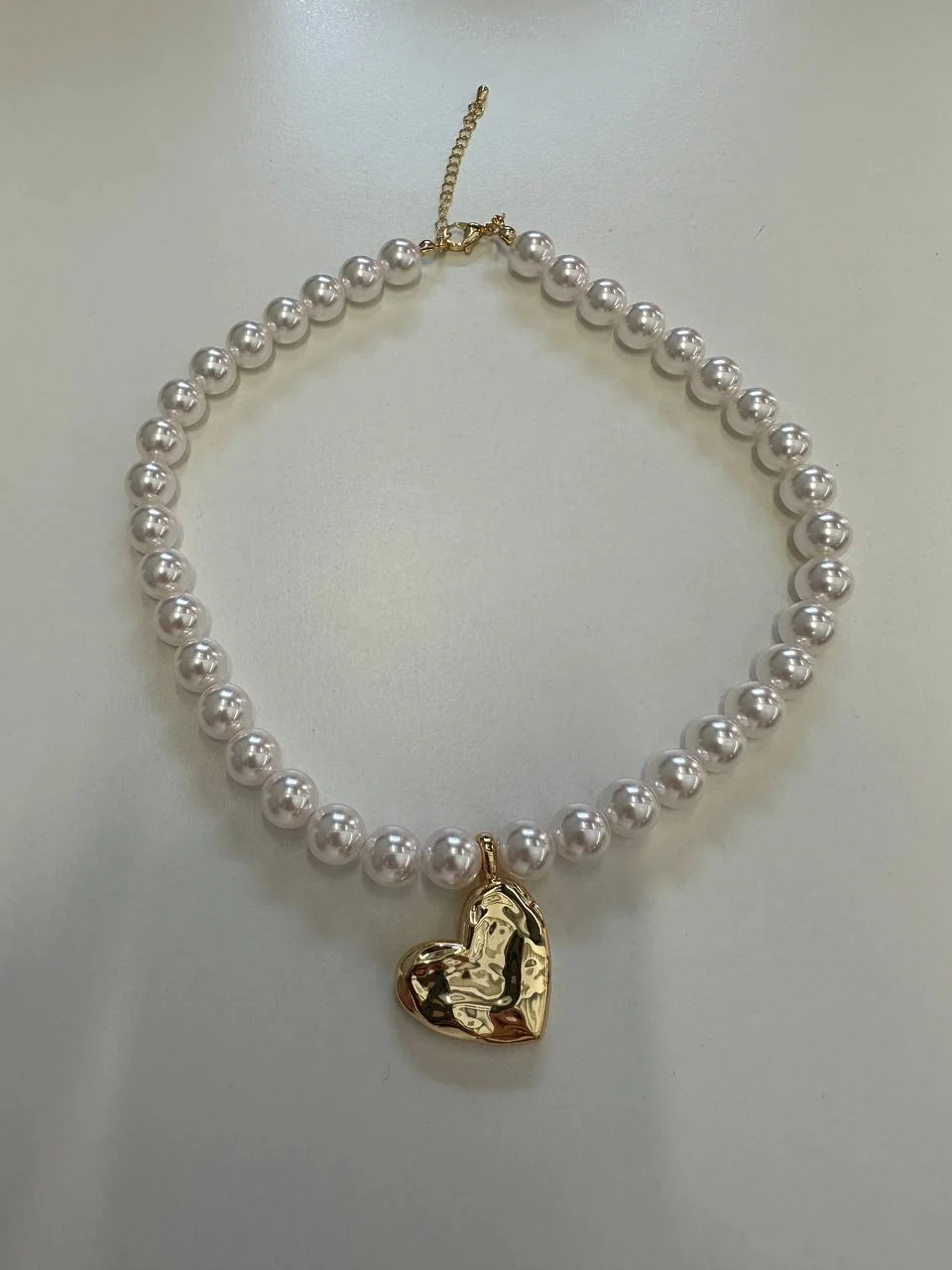 The same necklace, shot on a phone on a grey desk