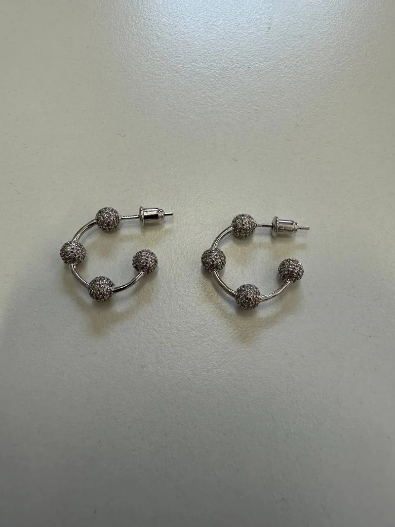 Earrings on a beige surface, shot on a phone