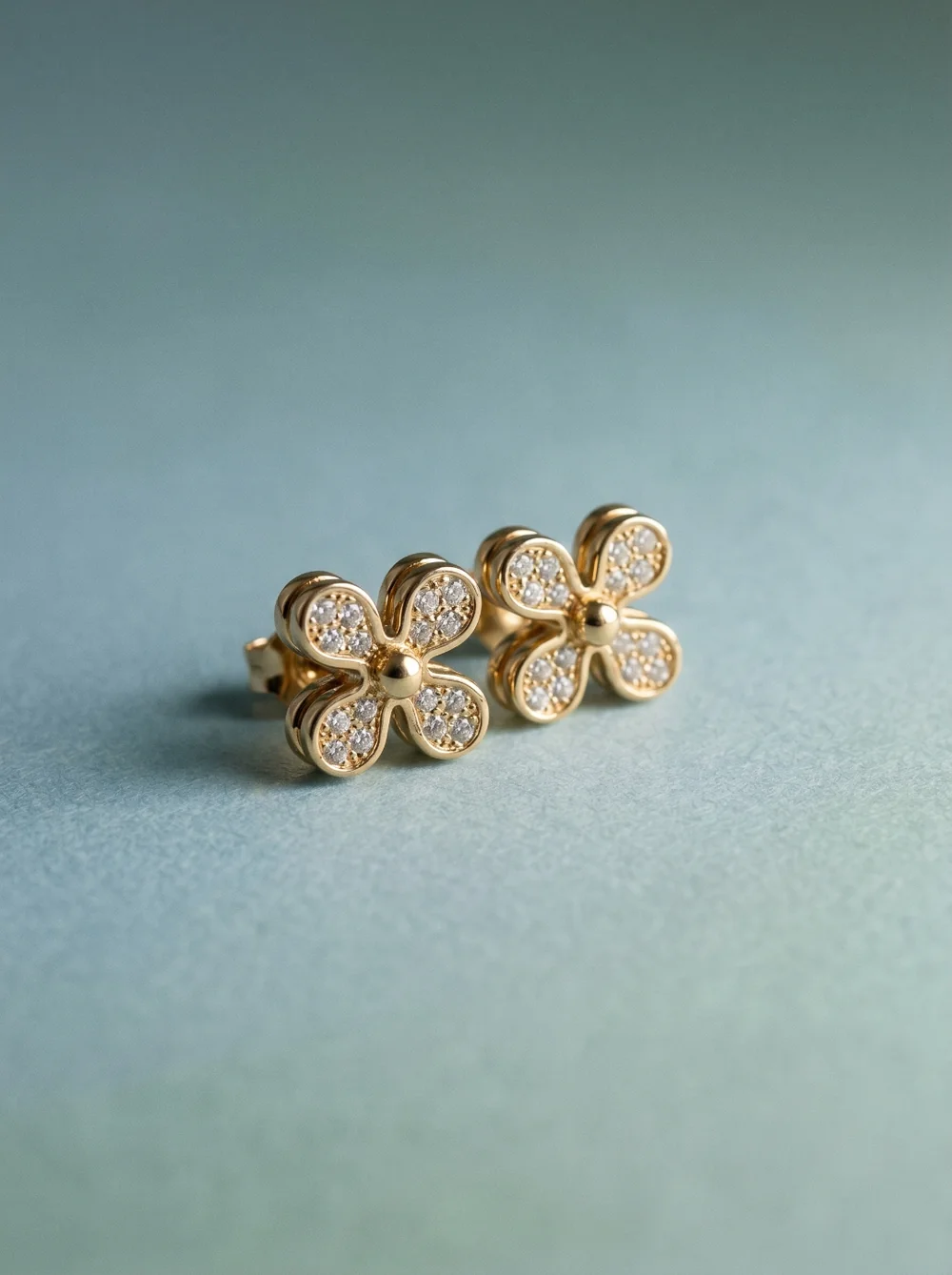 Product shot: gold flower earrings on an olive background